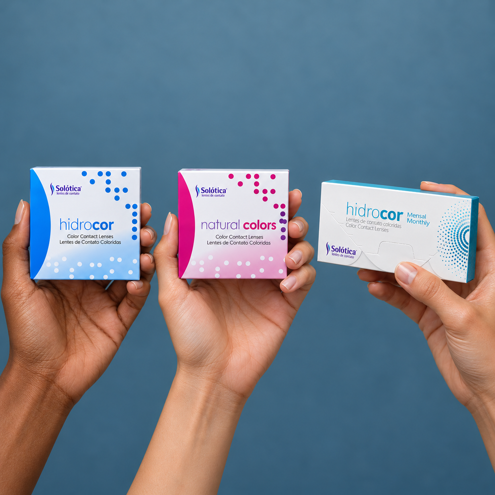 Hands holding Solótica Hidrocor and Natural Colors contact lens packages